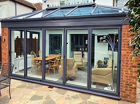 Grey aluminium conservatory with 5-panel bifold doors built and installed by Harrow Windows Ltd